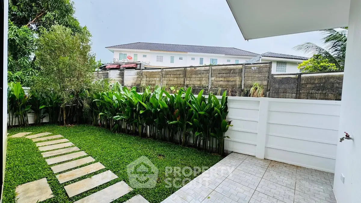 Charming garden view with lush greenery and modern fence in a serene residential area.