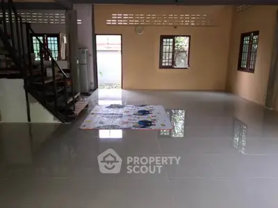 Spacious open-plan living area with tiled flooring and natural light.