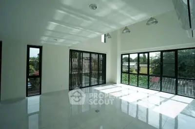 Spacious sunlit living room with large windows and modern lighting