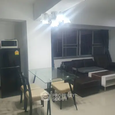 Modern living room with glass dining table and cozy seating area.