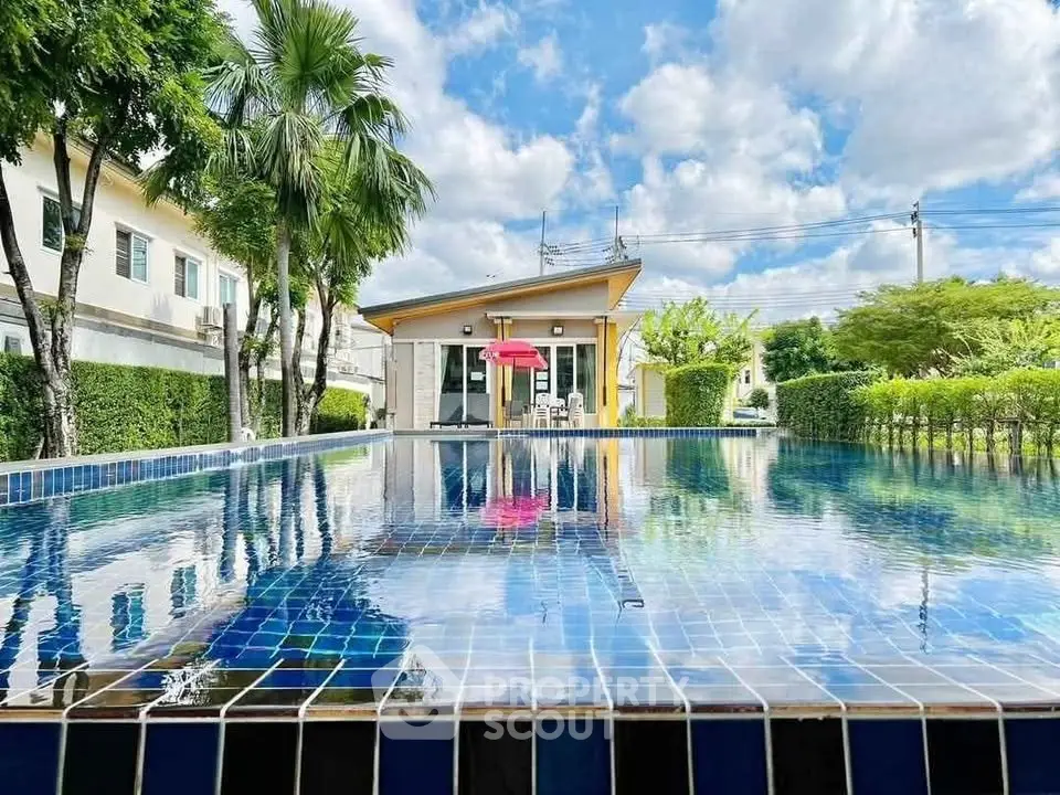 Stunning outdoor pool with lush greenery and modern building, perfect for relaxation and leisure.