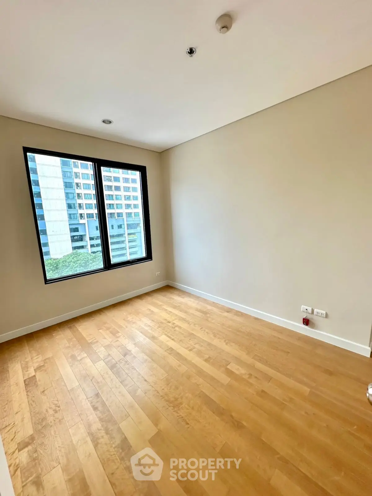 Spacious empty room with wooden flooring and large window in modern apartment