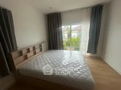 Spacious bedroom with large window and garden view, featuring a modern bed and elegant curtains.