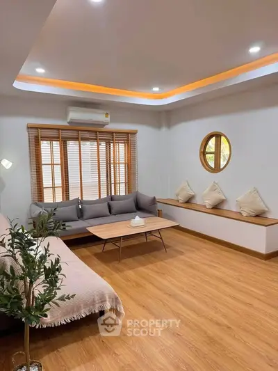 Modern living room with stylish furniture and wooden flooring, featuring a cozy seating area and elegant lighting.