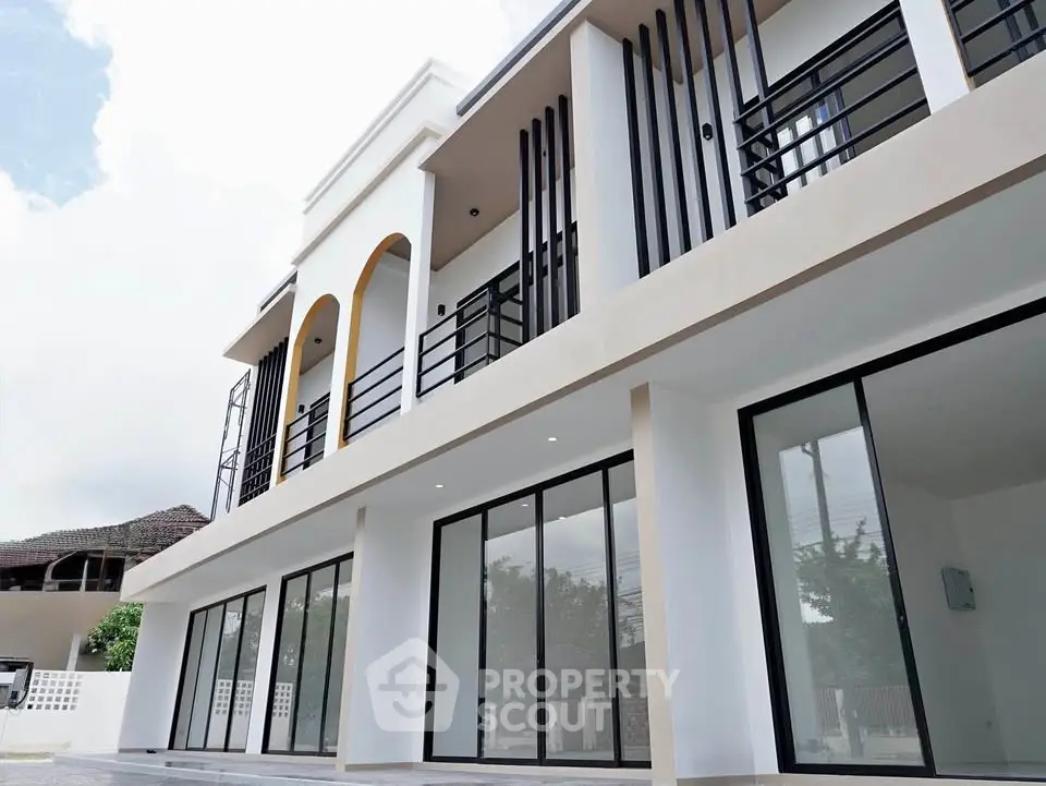 Modern two-story building with large glass windows and sleek balcony design.