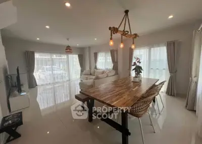 Spacious living room with modern decor and natural light, featuring a stylish dining area and cozy seating.