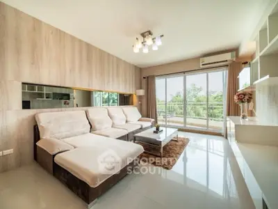 Spacious living room with modern decor and large windows overlooking greenery.