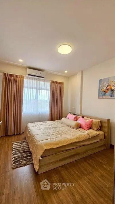 Cozy bedroom with wooden flooring, large window, and elegant decor in modern apartment.