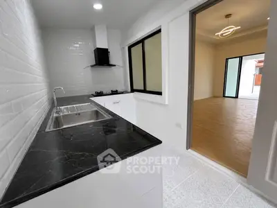 Modern kitchen with sleek black countertop and open layout to spacious living area.
