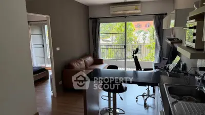 Modern open-plan living room with kitchen and balcony view, featuring stylish furniture and natural light.