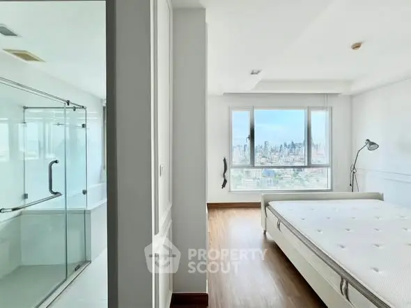 Modern bedroom with city view and adjacent glass shower