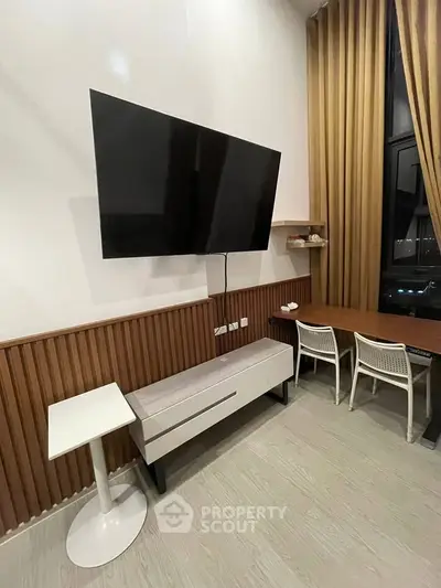 Modern living room with wall-mounted TV, stylish furniture, and elegant curtains.