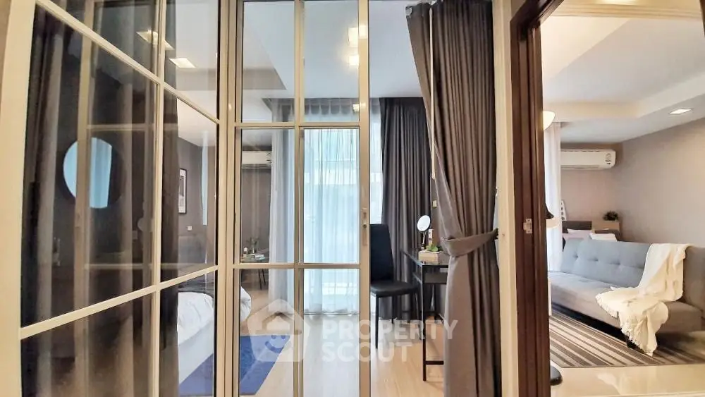 Modern apartment interior with glass partition, cozy living area, and stylish decor.