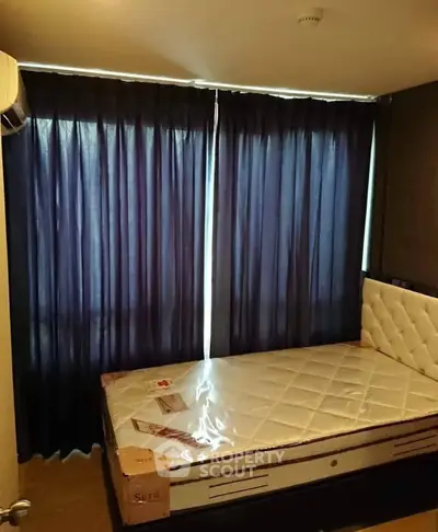 Cozy bedroom with a comfortable mattress and dark curtains for privacy.