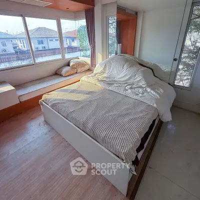 Cozy bedroom with large windows and natural light, featuring a comfortable bed and modern design.