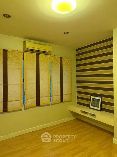 Spacious room with elegant wooden flooring and stylish wall design, featuring air conditioning and natural light.