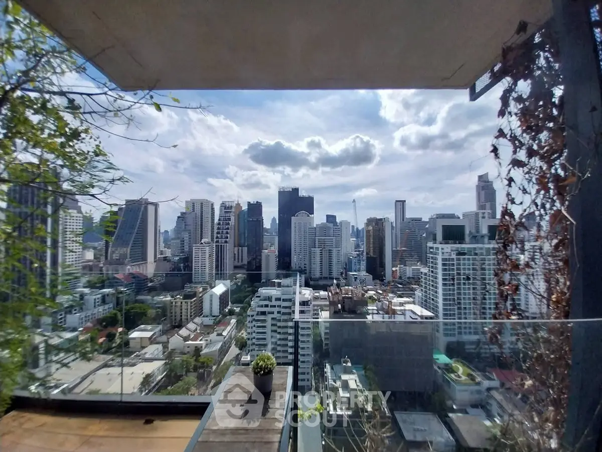 Stunning cityscape view from a modern balcony with glass railing and greenery.