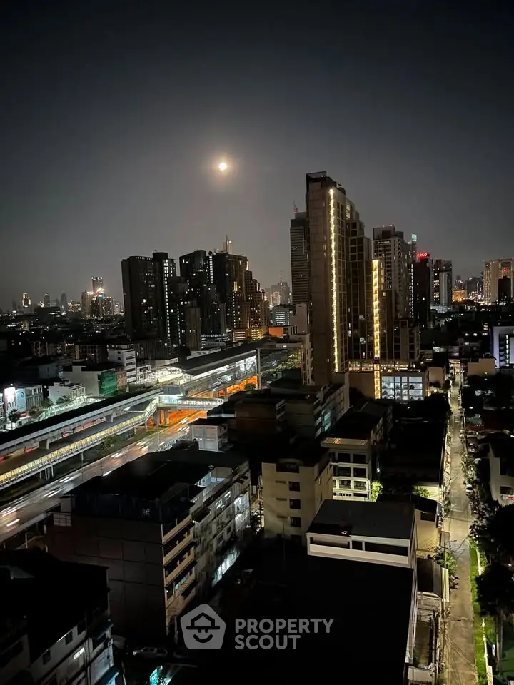 Stunning cityscape view of illuminated skyscrapers at night with a full moon, showcasing urban living.