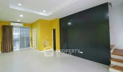 Spacious modern living room with vibrant yellow walls and sleek staircase