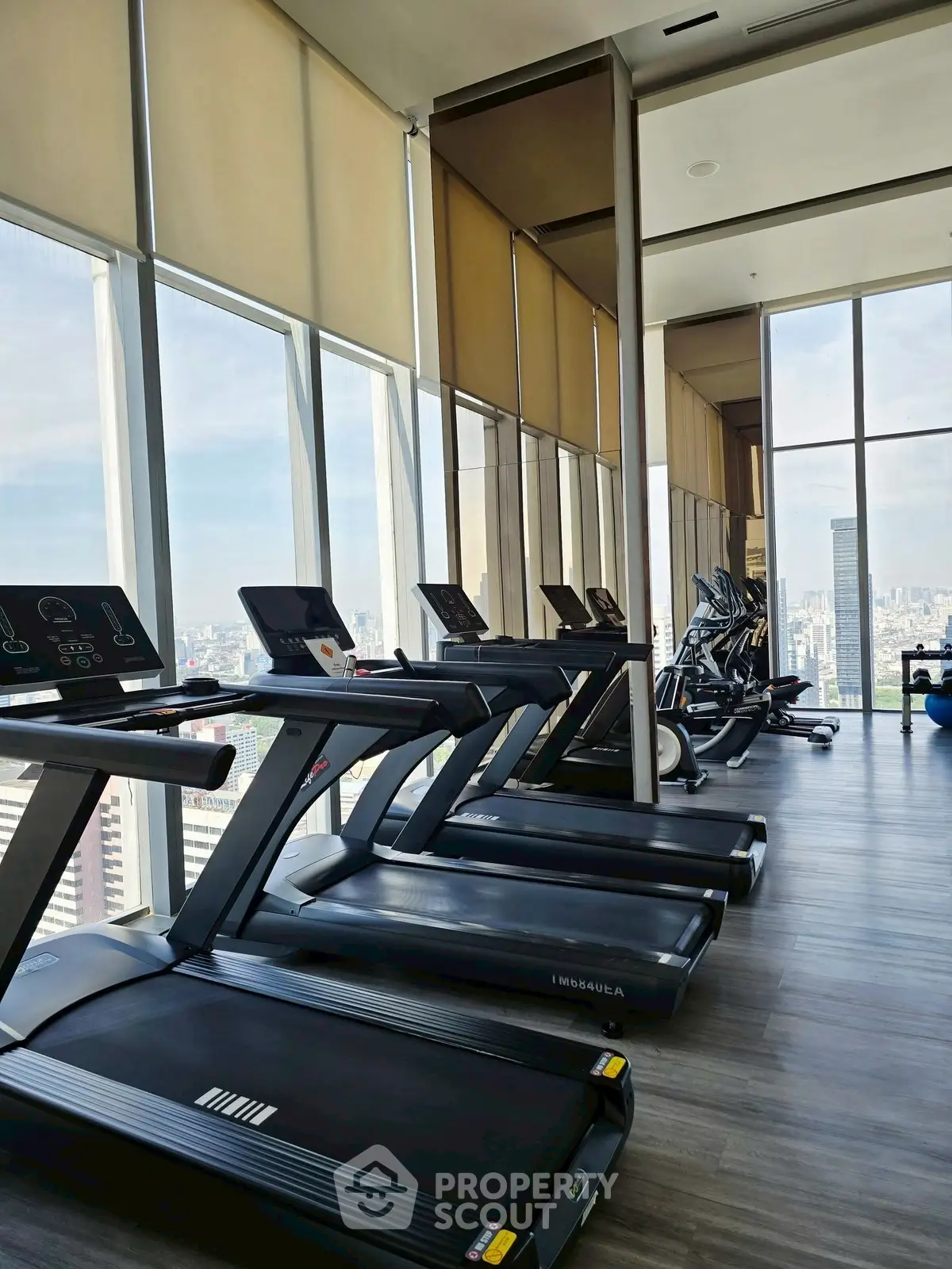Modern gym with city view and state-of-the-art equipment in luxury high-rise building.