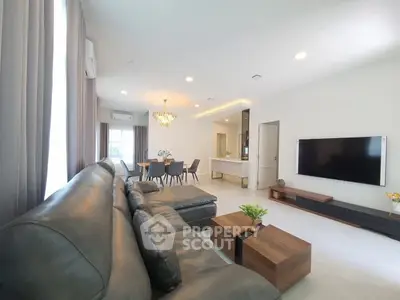 Spacious modern living room with leather sofa and wall-mounted TV in open layout.