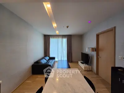 Modern living room with sleek furniture and natural light, featuring a marble dining table and stylish decor.