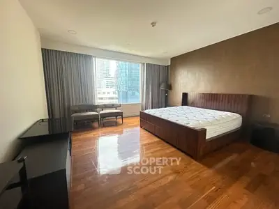 Spacious bedroom with modern furnishings and city view, featuring hardwood floors and elegant decor.