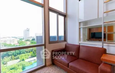 Modern living room with large windows and city view, featuring a brown leather sofa.