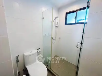 Modern bathroom with glass shower enclosure and sleek white tiles