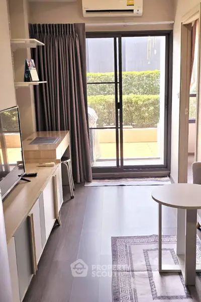 Modern living room with sliding glass doors leading to a garden view, featuring sleek furniture and natural light.