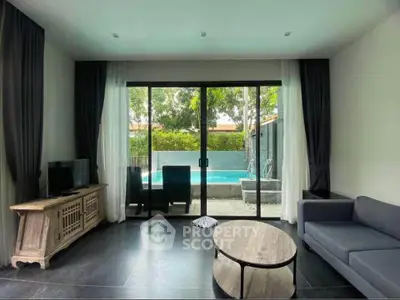 Modern living room with pool view, stylish furniture, and large glass doors.