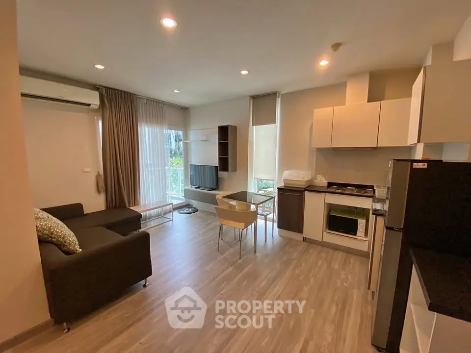 Modern open-layout living room and kitchen with sleek furniture and natural light.