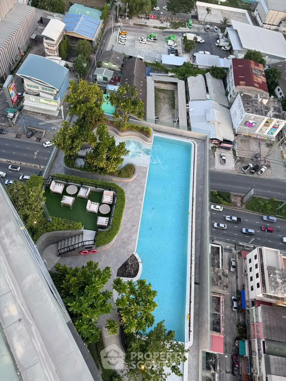 Stunning aerial view of rooftop pool with lush greenery and cityscape backdrop.