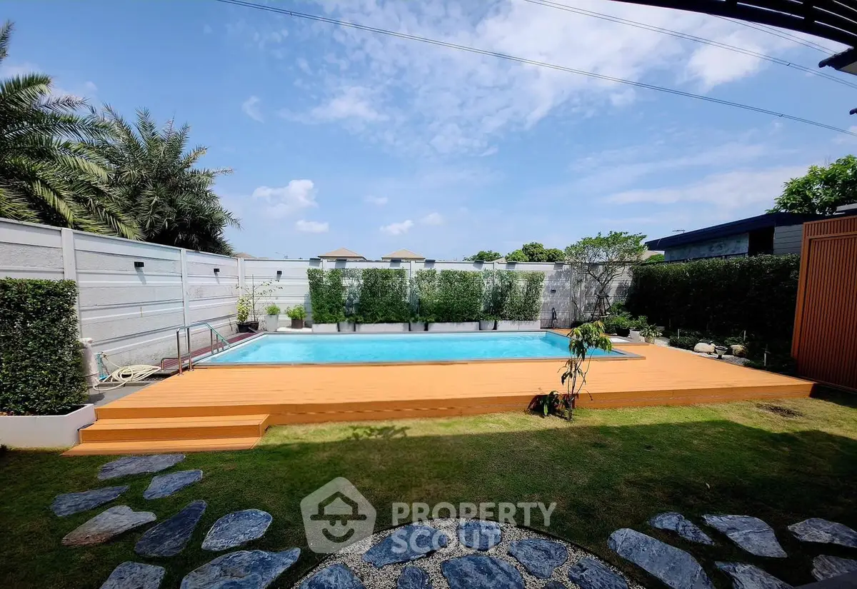 Luxurious private pool with wooden deck and lush greenery in a serene backyard setting.