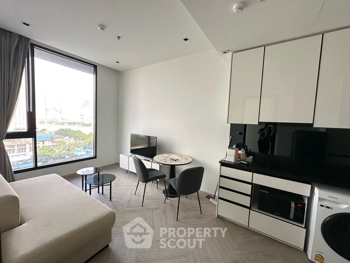 Modern living room with city view, featuring sleek furniture and large window.