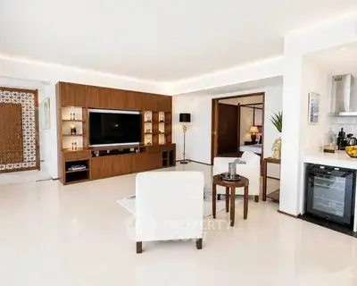Spacious modern living room with elegant decor and open layout, featuring a large TV and stylish furniture.