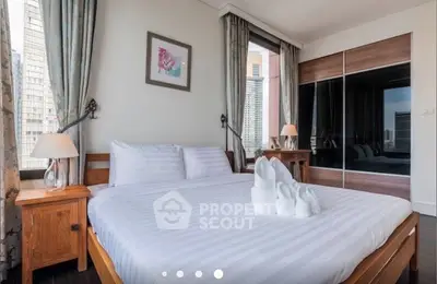 Spacious bedroom with large bed, elegant decor, and city view windows.