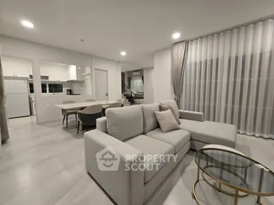 Modern living room with elegant decor and open kitchen layout, featuring a cozy sofa and stylish dining area.