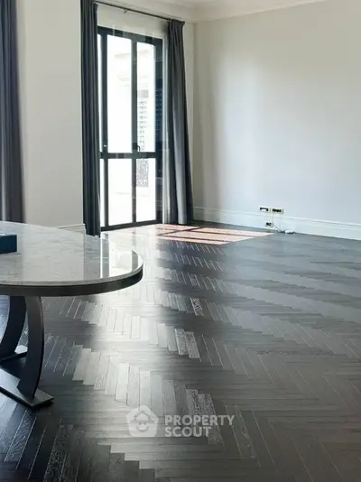 Spacious living room with elegant dark wood flooring and large window