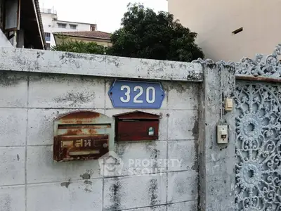 Charming vintage entrance with rustic mailboxes and ornate gate at house number 320.