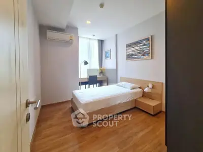 Modern bedroom with wooden flooring and natural light