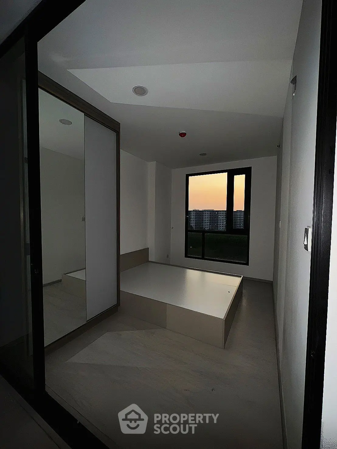 Modern minimalist bedroom with sunset view and sleek mirrored wardrobe.