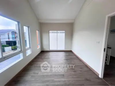 Spacious empty room with large windows and wood flooring, perfect for customization.
