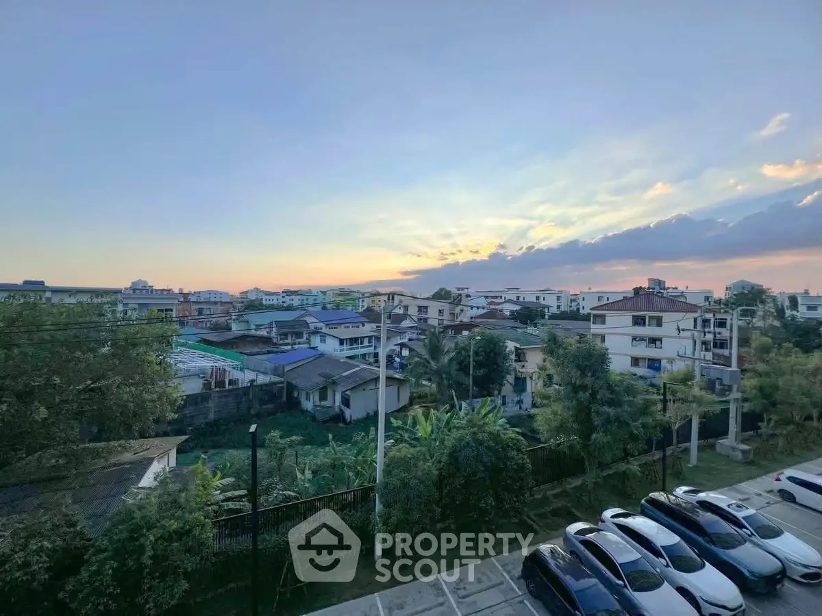 Stunning sunset view over suburban neighborhood with lush greenery and parked cars.