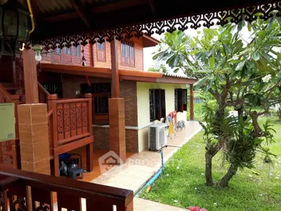 Charming traditional wooden house with lush garden and intricate balcony design.