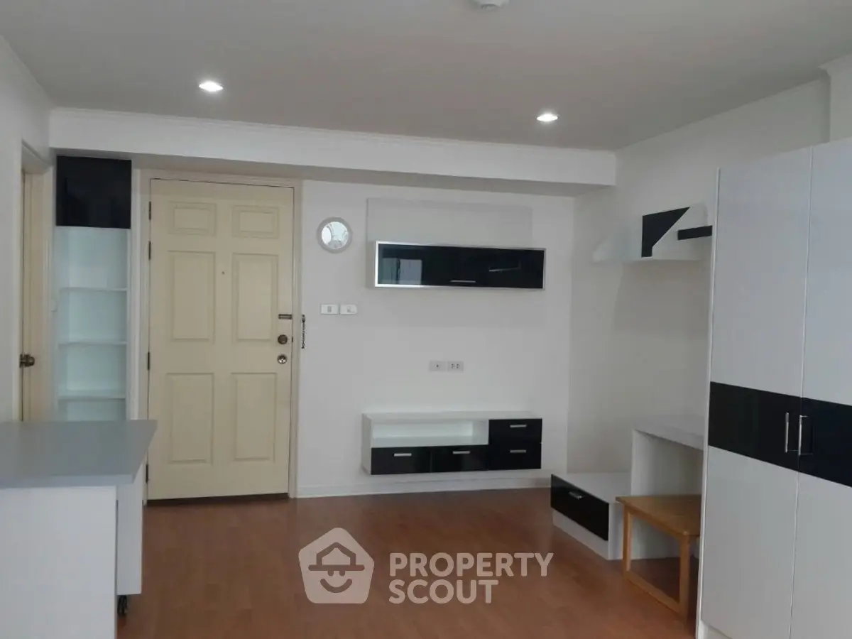 Modern minimalist living room with sleek black and white furniture and wooden flooring.