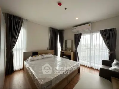 Spacious bedroom with modern furnishings and large windows for natural light.