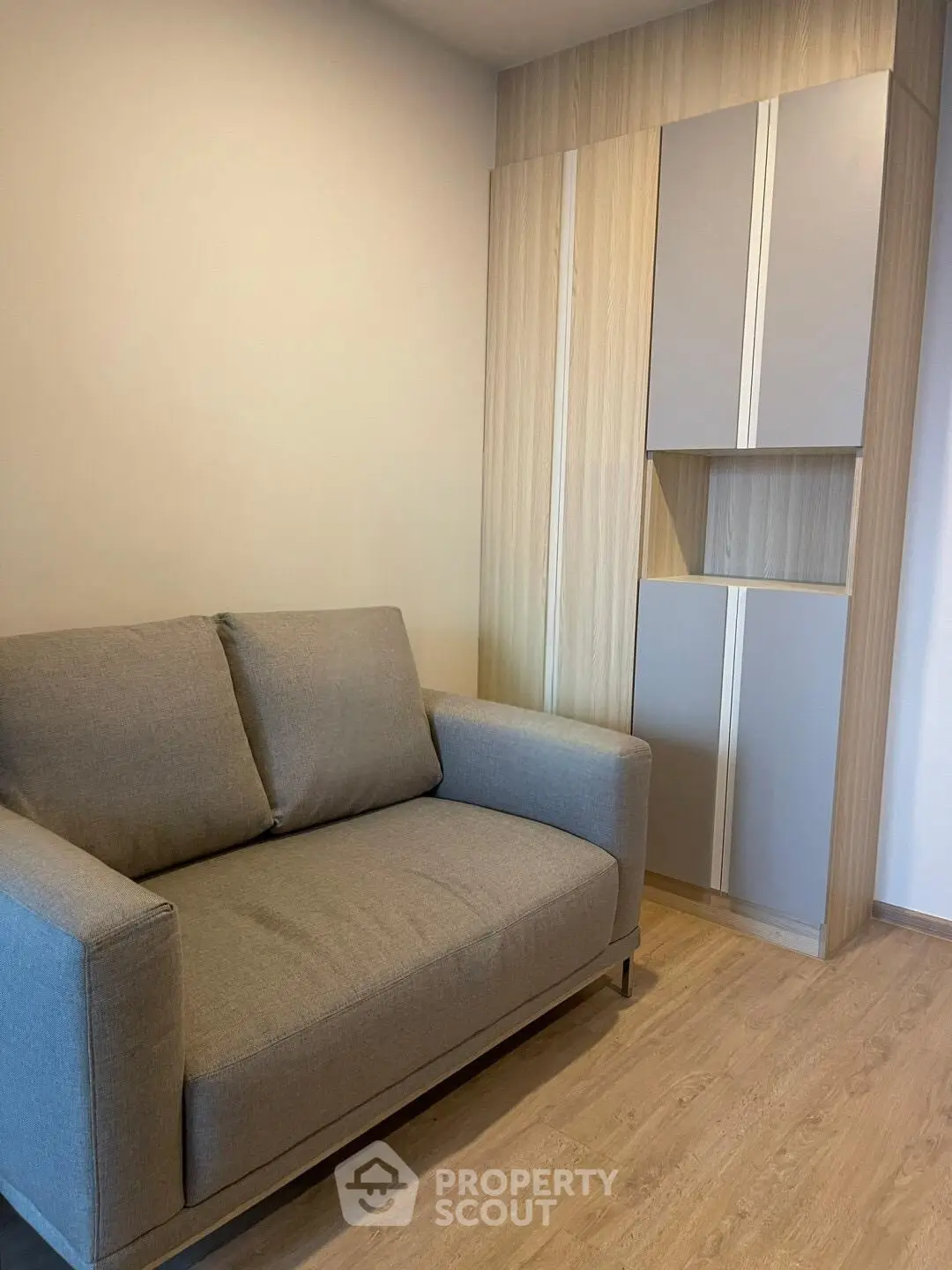 Modern living room with stylish gray sofa and sleek wooden storage unit.