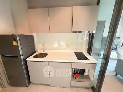 Modern compact kitchen with sleek cabinetry and built-in appliances in a stylish apartment.