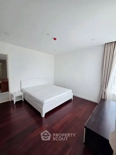 Spacious bedroom with hardwood floors and natural light in modern apartment